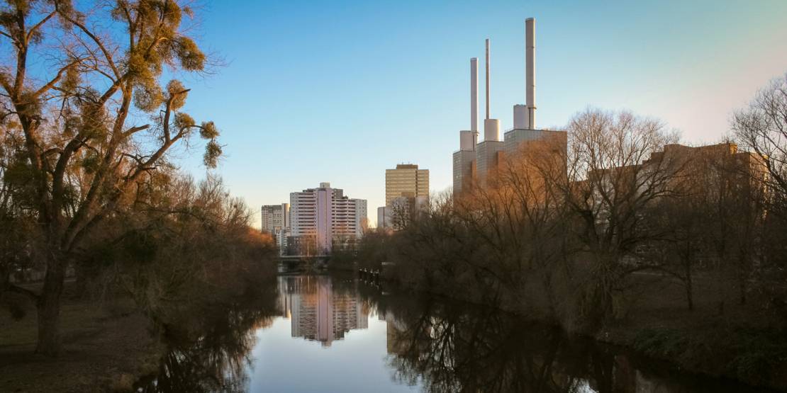 Blick auf ein Fluss mit kahlen Bäumen am Ufer, im Hintergrund das Ihmezentrum.